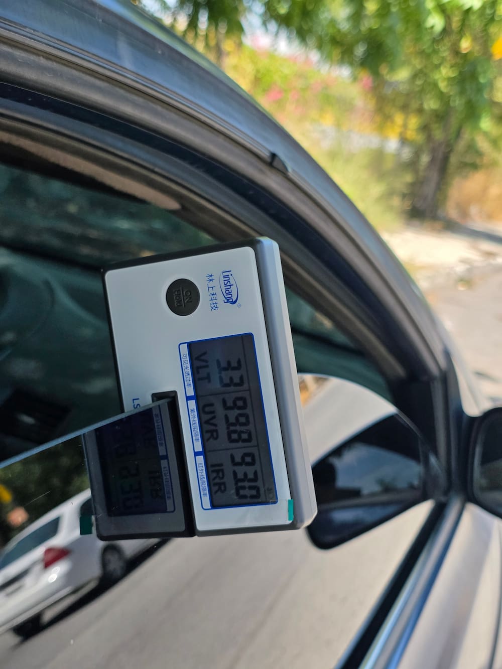 Medidor de transmisión montado sobre el cristal de un auto mostrando la lectura de VLT, UV e infrarrojo